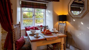 A dining area with a table set for breakfast, including croissants, strawberries, and a coffee pot.
