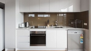 Una cocina moderna con armarios blancos, horno empotrado, lavavajillas y refrigerador.