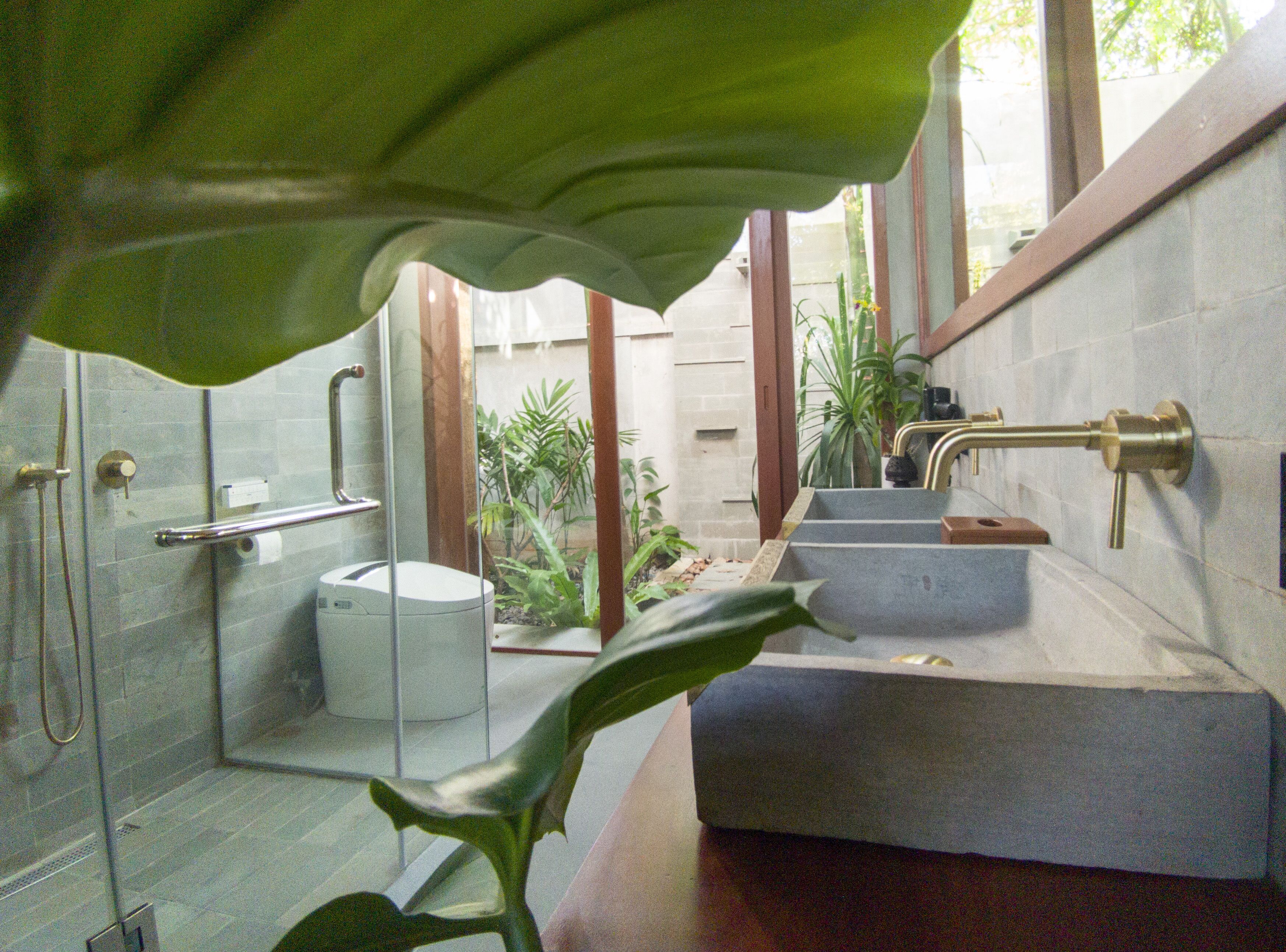 A modern bathroom with a glass shower enclosure, a toilet, and a sink with a marble countertop.