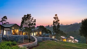 A modern resort with multiple buildings, stone pathways, and lush greenery. - WelcomHeritage Ayatana Ooty (Coonoor)