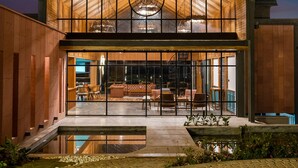 A modern building with a glass facade, a central atrium, and a pool area. - WelcomHeritage Ayatana Ooty (Coonoor)