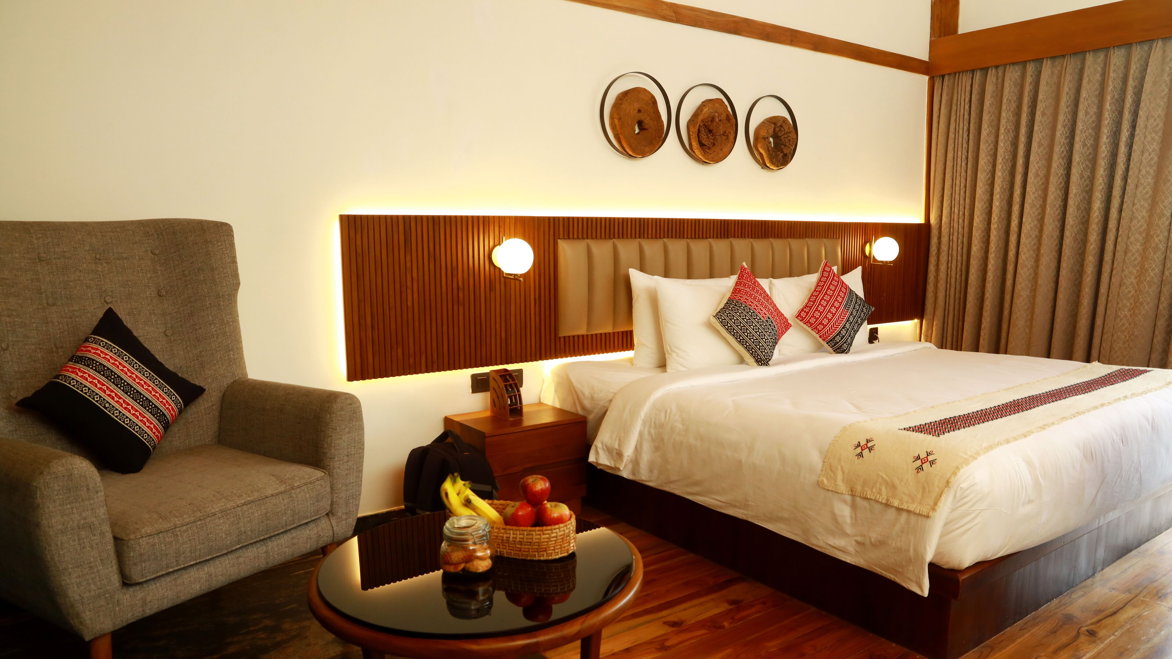 Una habitación de hotel con una cama, una silla, una mesita de noche y una pequeña mesa con fruta y una cesta.
