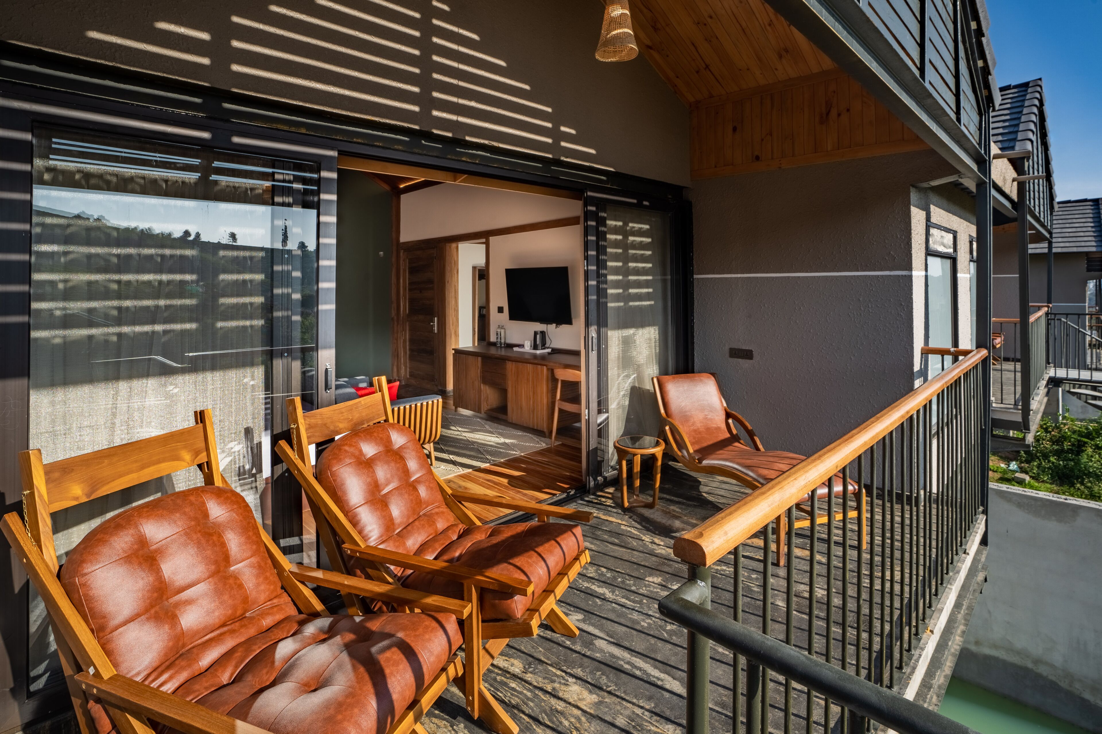 A balcony with wooden chairs, a small table, and a TV in the background.