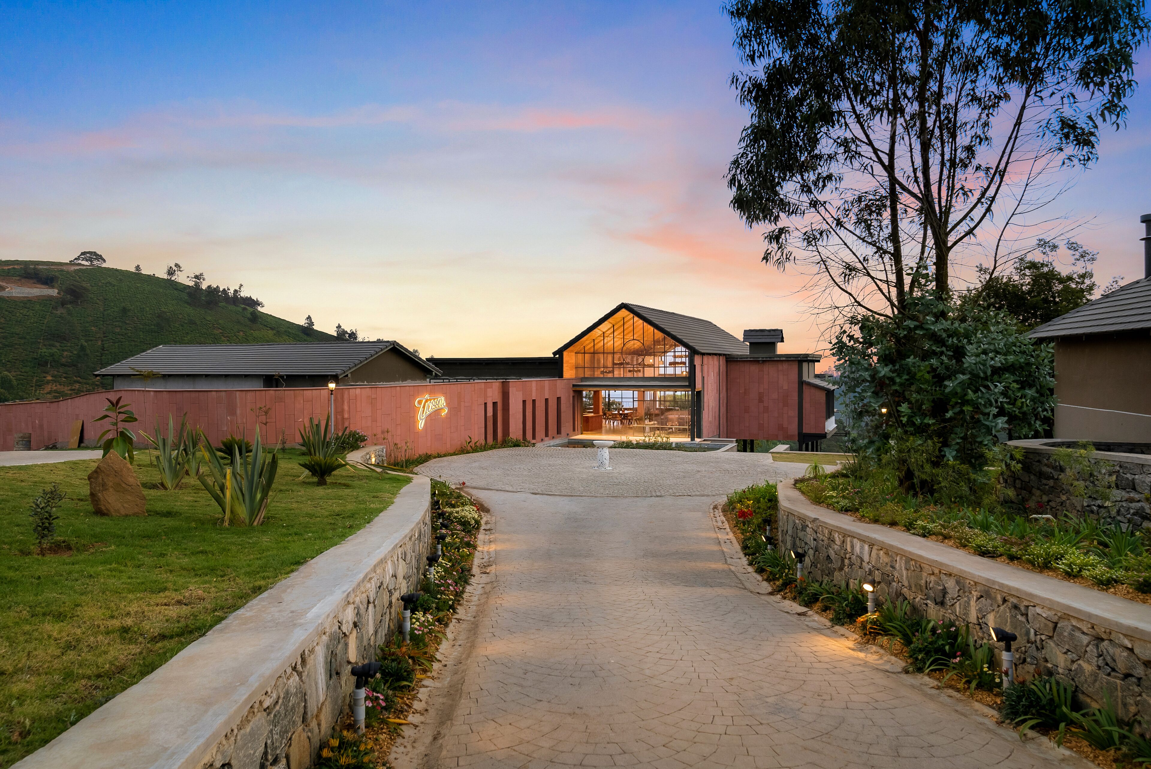 A building with a glass facade, a paved entrance, and a landscaped garden.