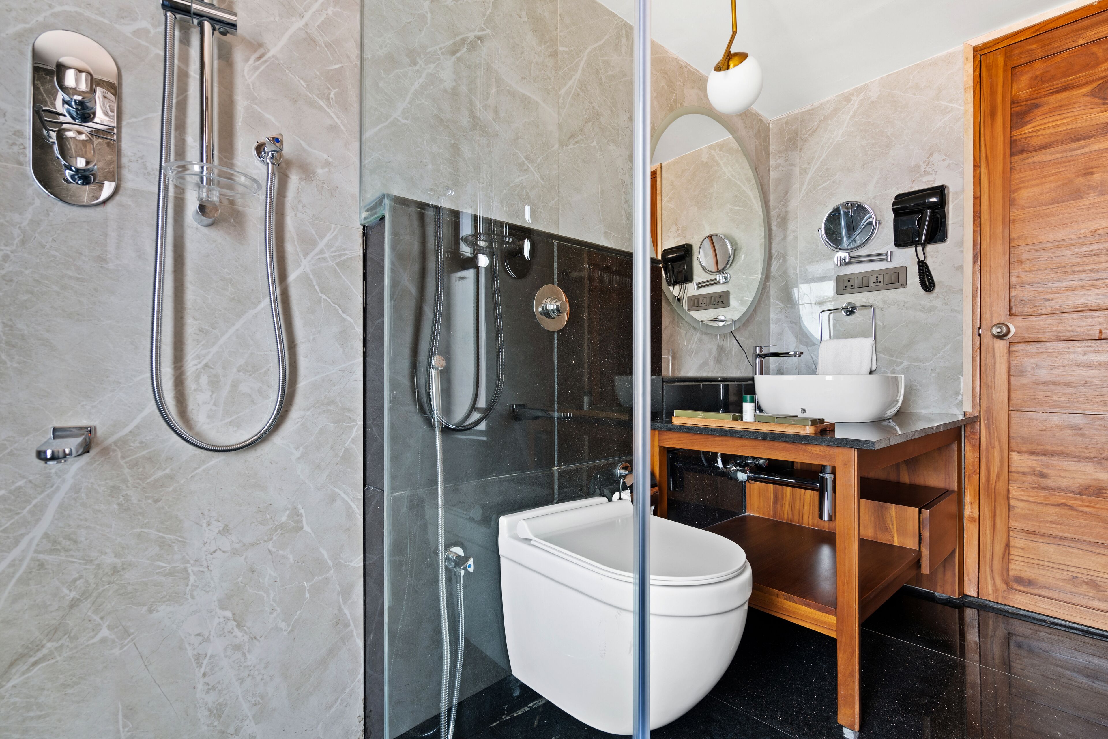 A modern bathroom with a glass-enclosed shower, a white toilet, and a wooden vanity with a sink.