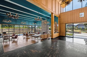 A spacious lobby with modern furniture, large windows, and a wooden accent wall.