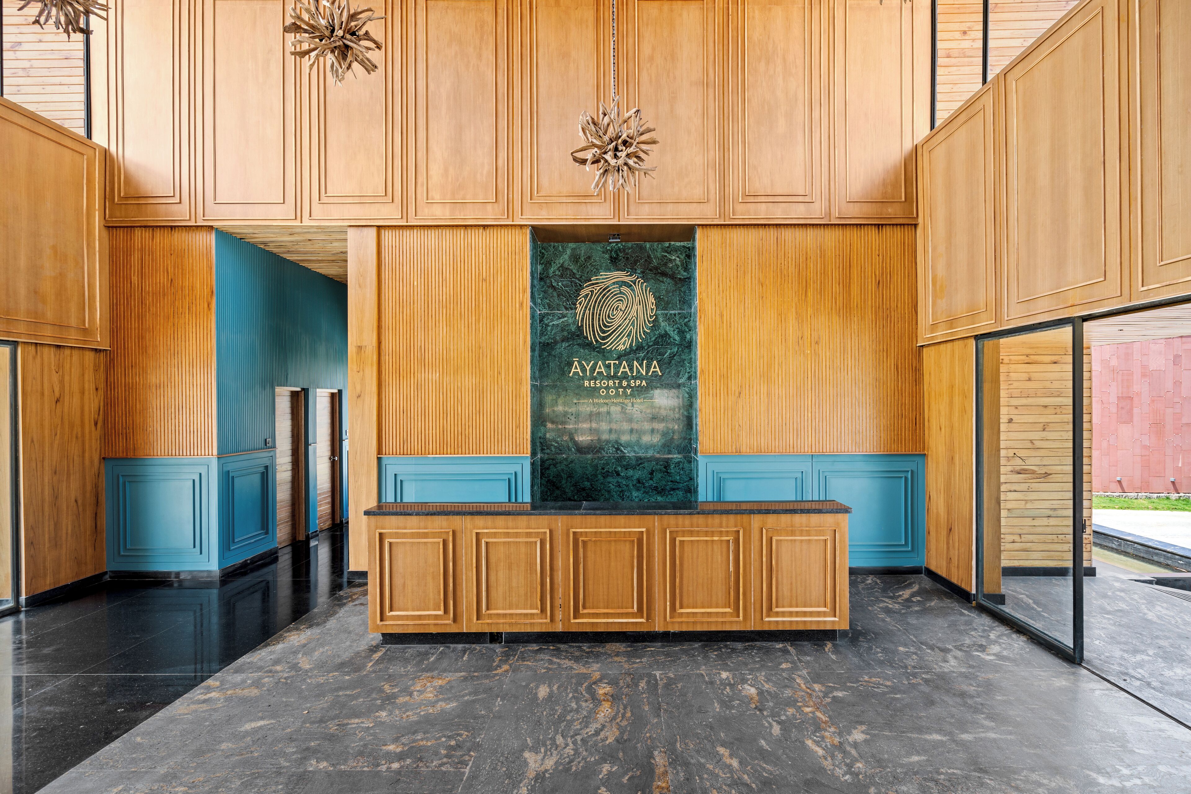 Ein Empfangsbereich mit Holzwandverkleidung, einer Marmor-Theke und dem Logo von Ayatana Resort & Spa.