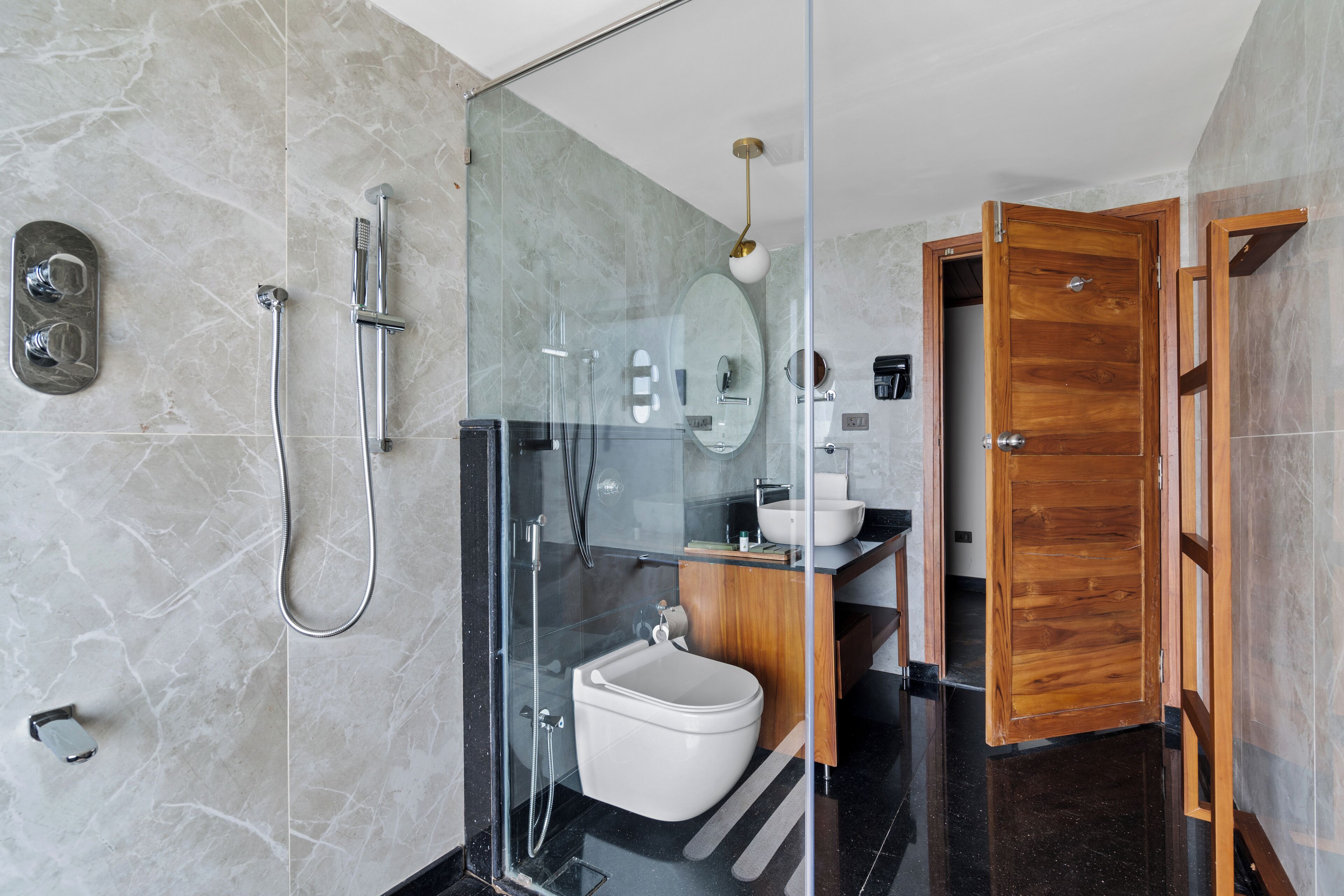 Ein modernes Badezimmer mit einer Duschkabine aus Glas, einer Toilette und einem Holzwaschtisch.