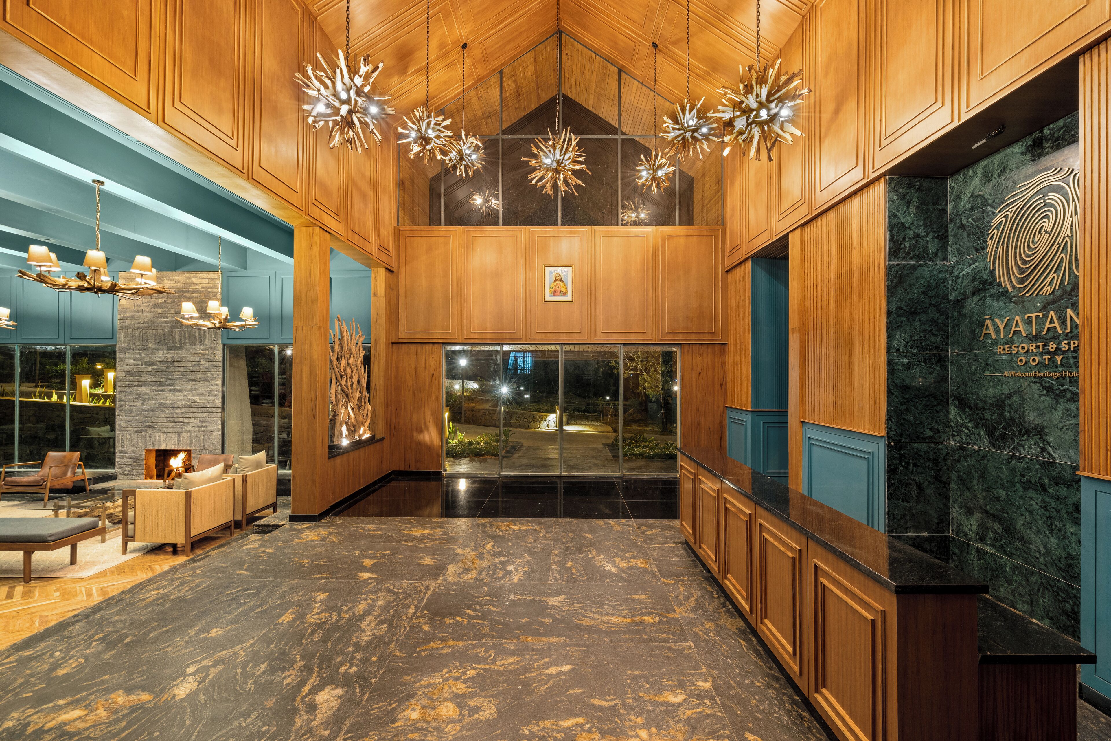 A lobby with wooden paneling, a stone fireplace, and a reception desk with a marble counter.