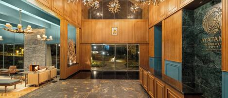 A lobby with wooden paneling, a stone fireplace, and a reception desk with a marble counter.