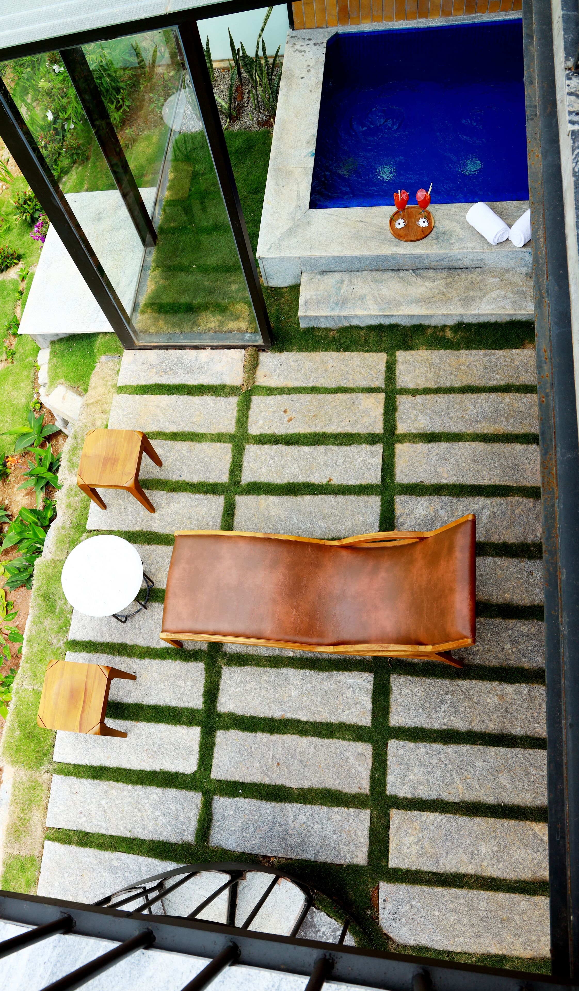 A rooftop terrace with a pool, seating area, and a view of the surrounding greenery.