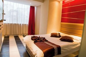 Ein Hotelzimmer mit einem großen Bett, einem roten Vorhang und einem modernen Kopfteil.