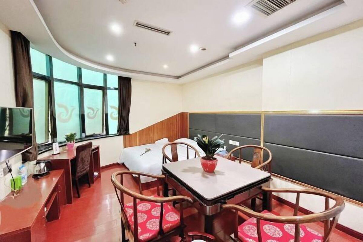 A hotel room with a dining area, a television, and a large window.
