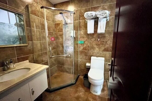 Un baño con ducha de vidrio, inodoro y lavamanos con espejo.