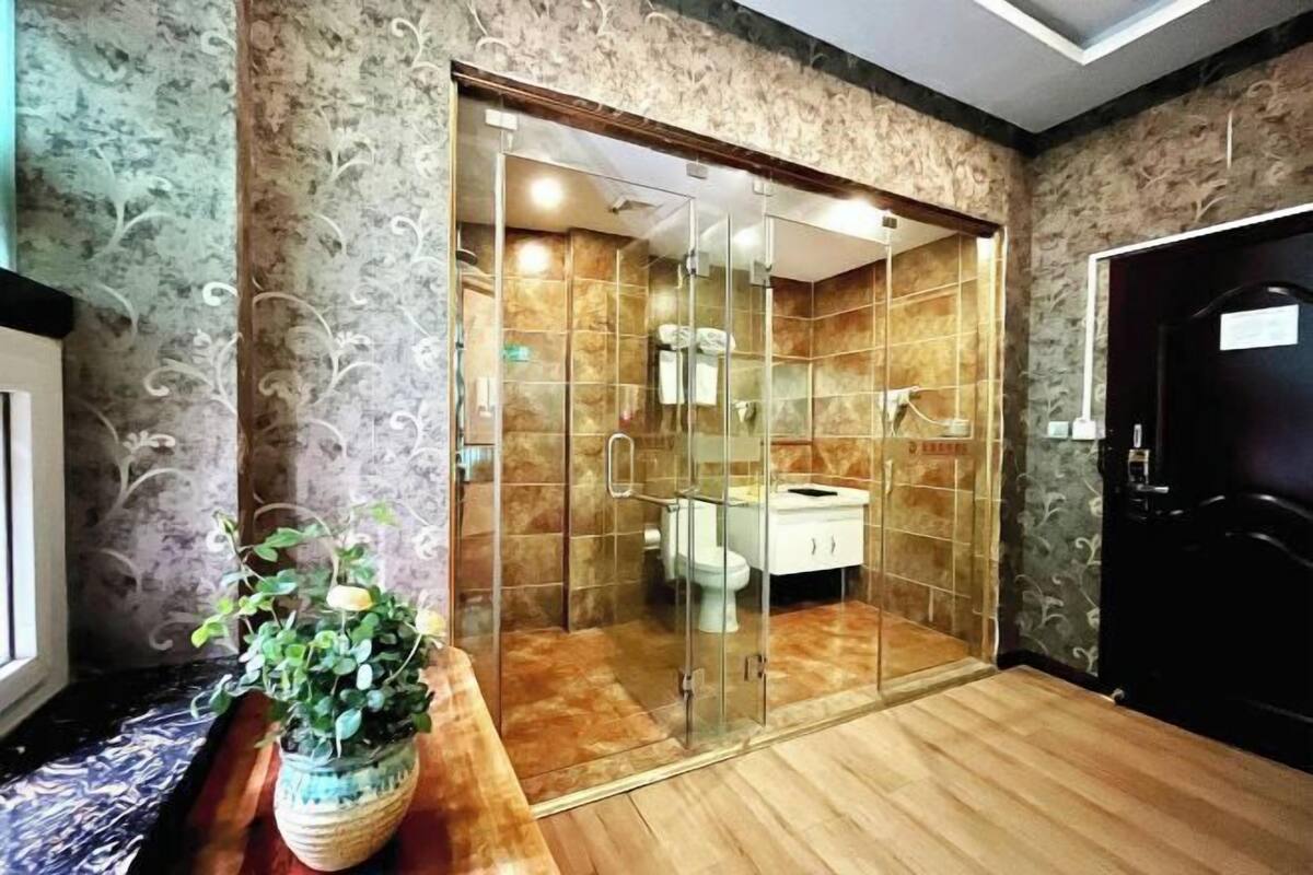 A bathroom with a glass-enclosed shower, a white sink, and a potted plant.