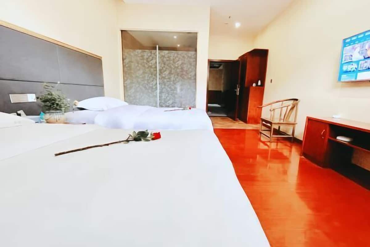 A hotel room with a bed, a desk, a chair, and a shower area.