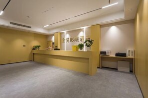 A reception area with a reception desk, a plant, and a microwave on a small table. - Jinyue Business Hotel (Chongqing)