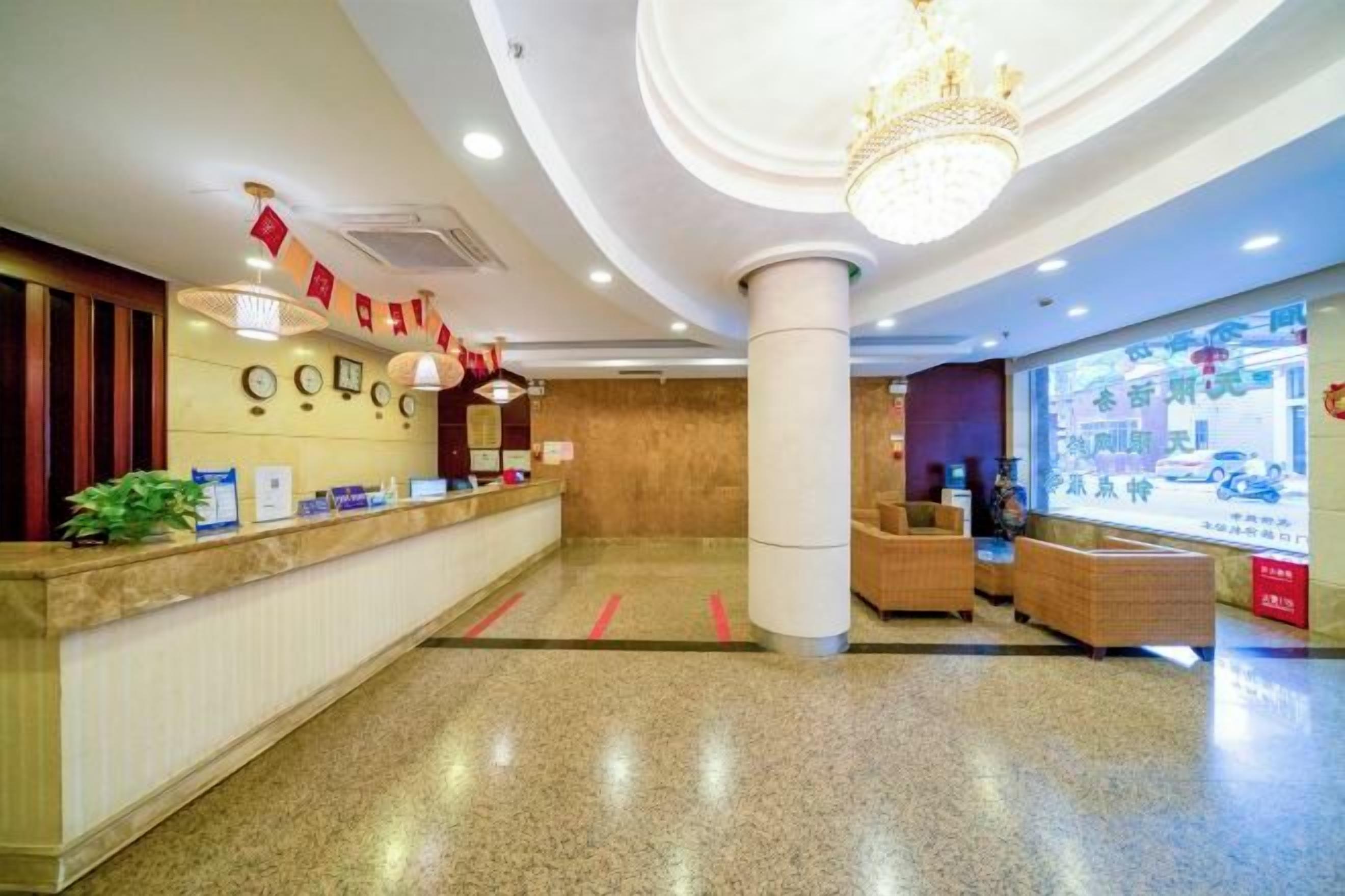 A hotel reception area with a marble counter, a chandelier, and a large window displaying a cityscape.