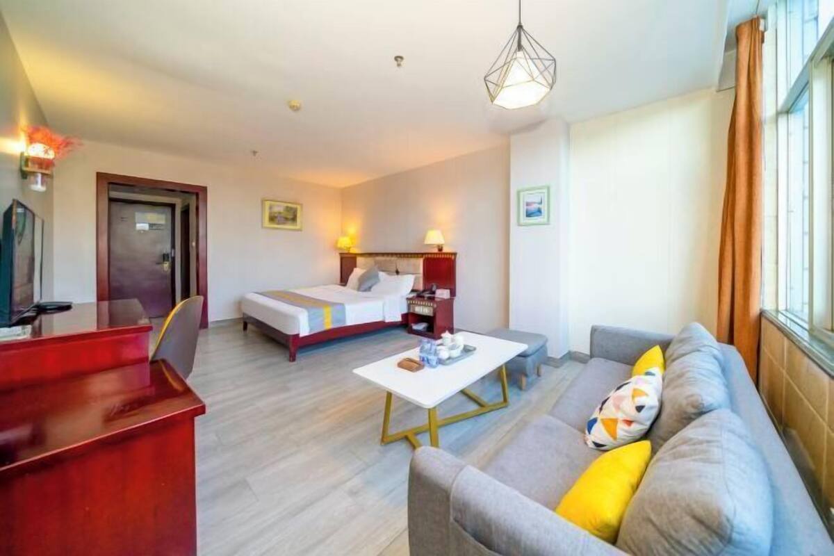 A hotel room with a bed, a sofa, a desk, and a window.