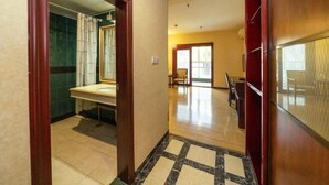 A hotel hallway with a marble-tiled floor, a wooden door frame, and a view into a bathroom with a green-tiled wall and a white sink. - Nan'an Furong Hotel (Guoguang High School Meishan Bus Station) (Nan'an)