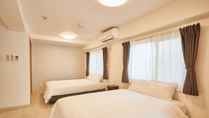 A hotel room with two beds, a ceiling air conditioner, and a window with curtains. - New Normal Hotel in NAGO (Nago)