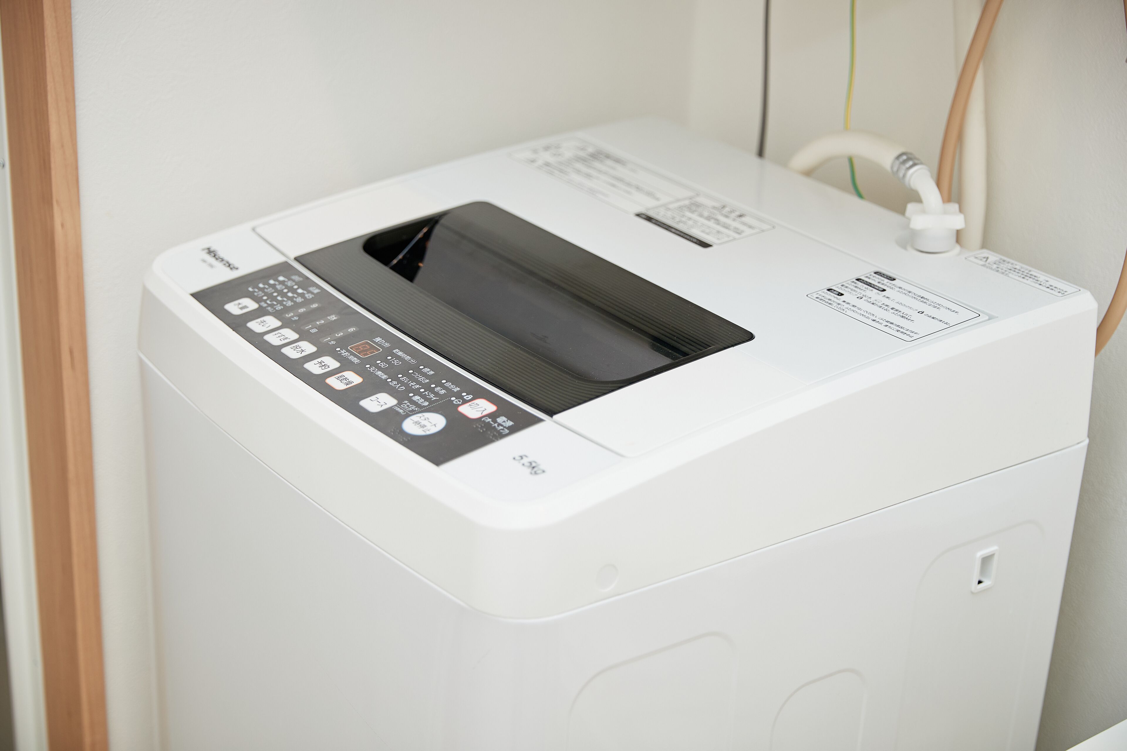 Uma máquina de lavar compacta, branca e fixa na parede, com painel de controle e porta transparente.