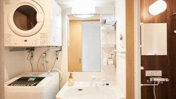 Une petite salle de bain équipée d’un lave-linge, d’un lavabo et d’un espace douche.