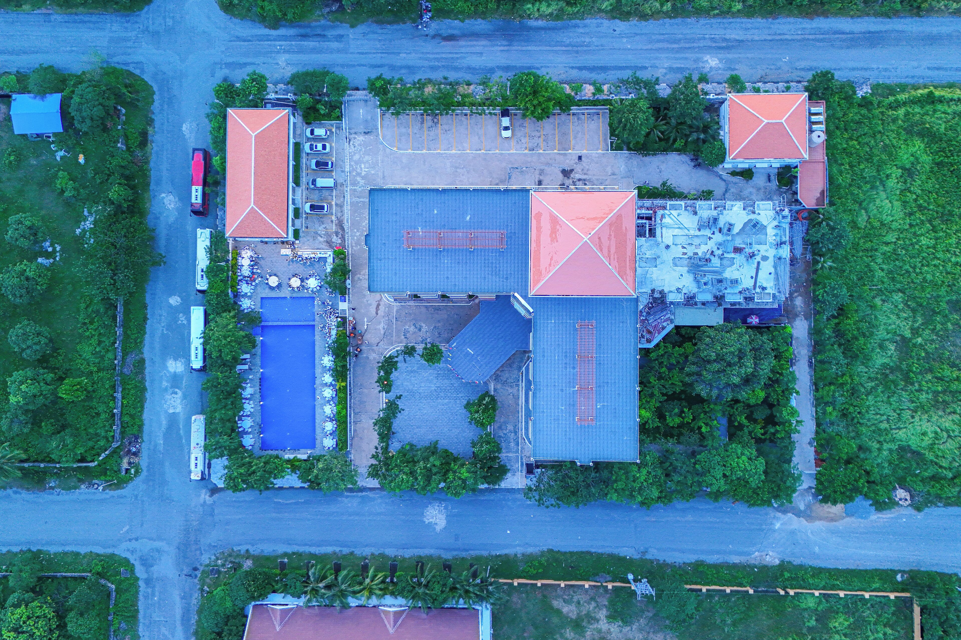 An aerial view of a building complex with multiple buildings, parking areas, and surrounding greenery.