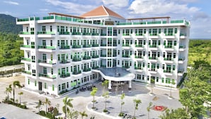 Un hotel de varios pisos con un patio central, rodeado de abundante vegetación y un paisaje montañoso.