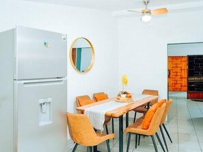 A modern kitchen with a refrigerator, a dining table with chairs, a ceiling fan, and a mirror on the wall. - Top Rated Home in Quezaltepeque, only 15 min away from San Salvador 🌅 (Quezaltepeque)
