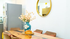 A dining area with a wooden table, six chairs, a vase with flowers, a thank you card, and a mirror on the wall.