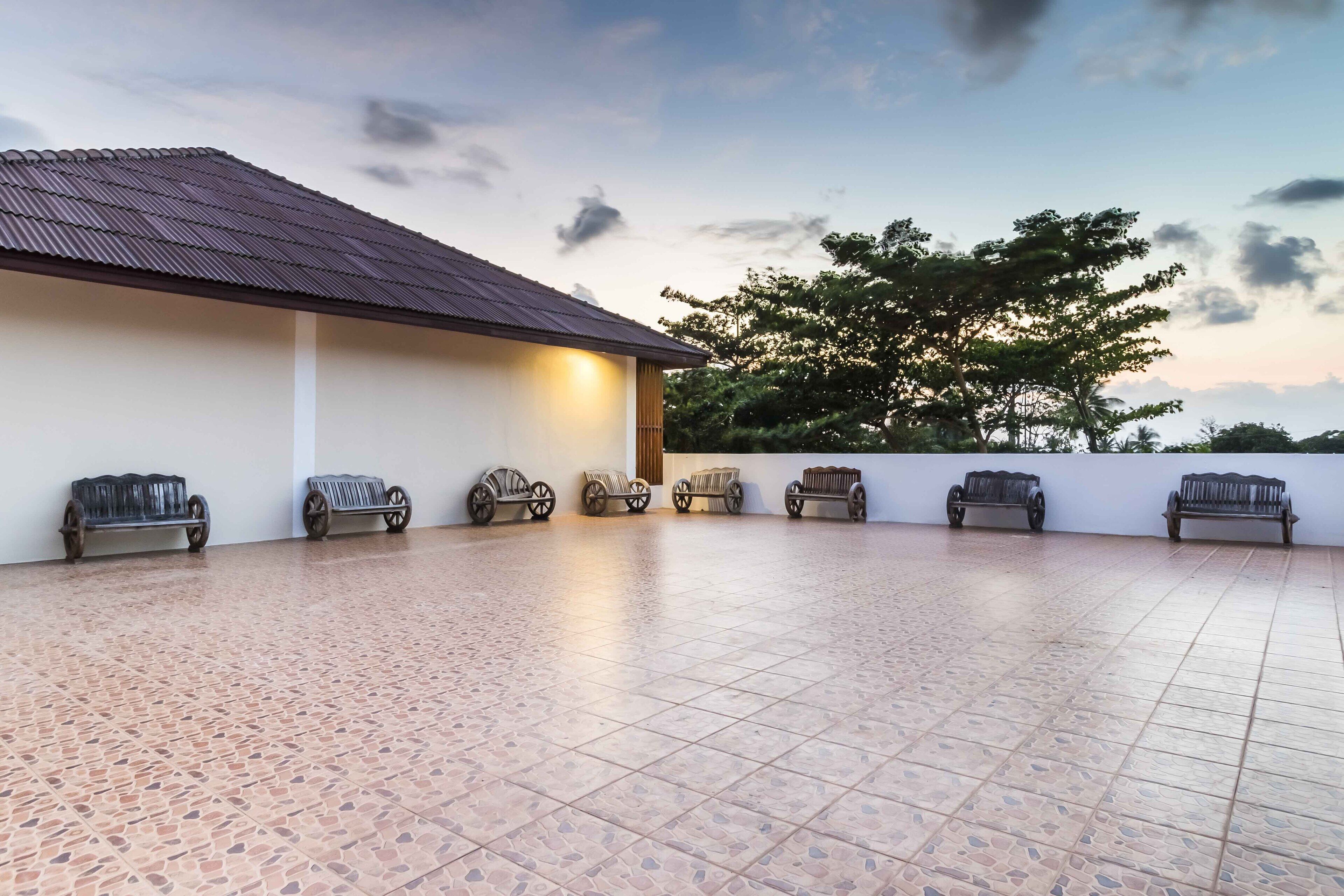 A spacious outdoor area with a tiled floor and several benches along the perimeter.