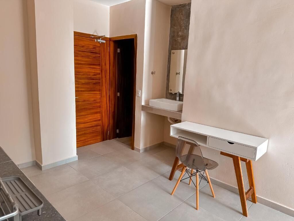 Un baño moderno con puerta de madera, lavamanos y espejo.