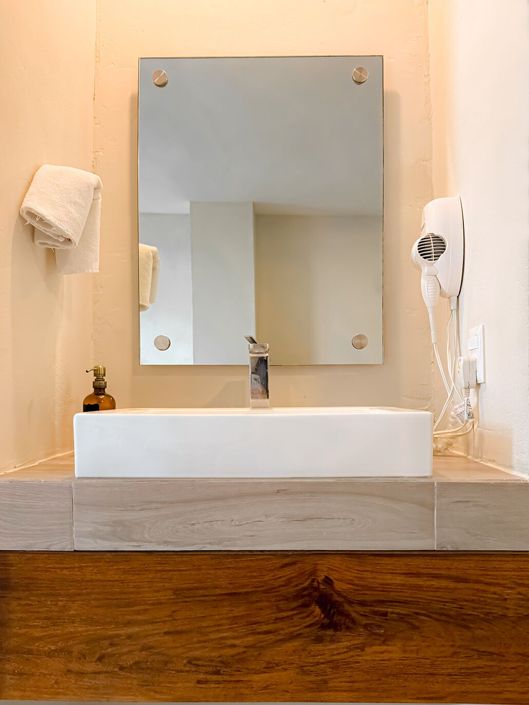 A bathroom with a white sink, a mirror, a towel, and a hairdryer.