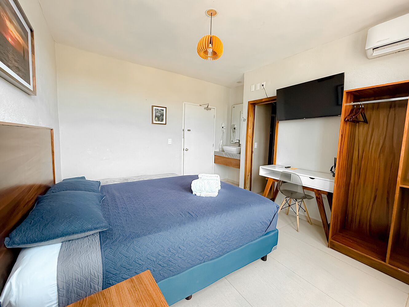 A bedroom with a bed, a desk, a wardrobe, and a television.