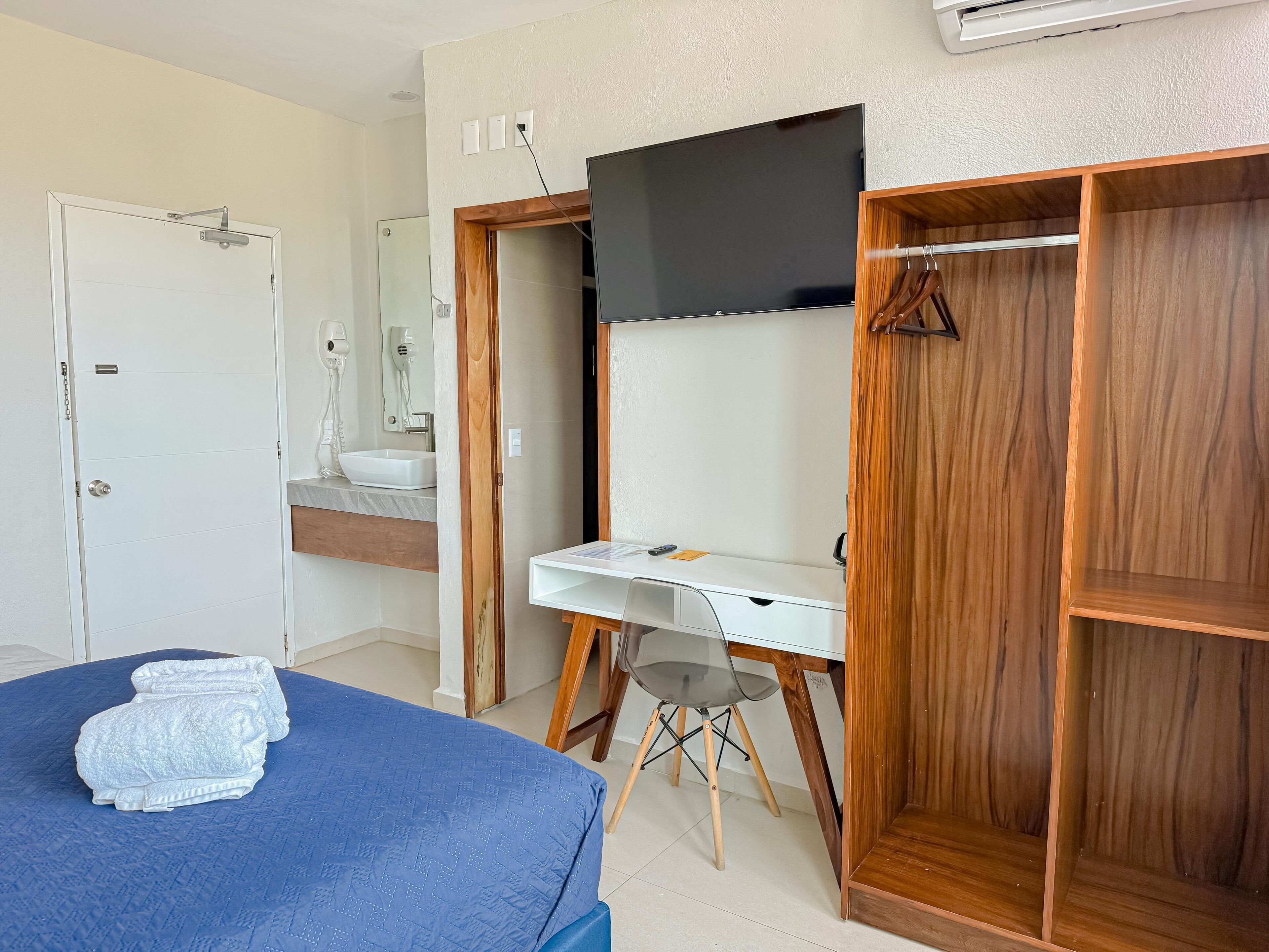 Un dormitorio con cama, escritorio, armario y baño.