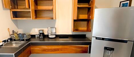 A modern kitchen with wooden cabinets, a stainless steel refrigerator, and a built-in sink.
