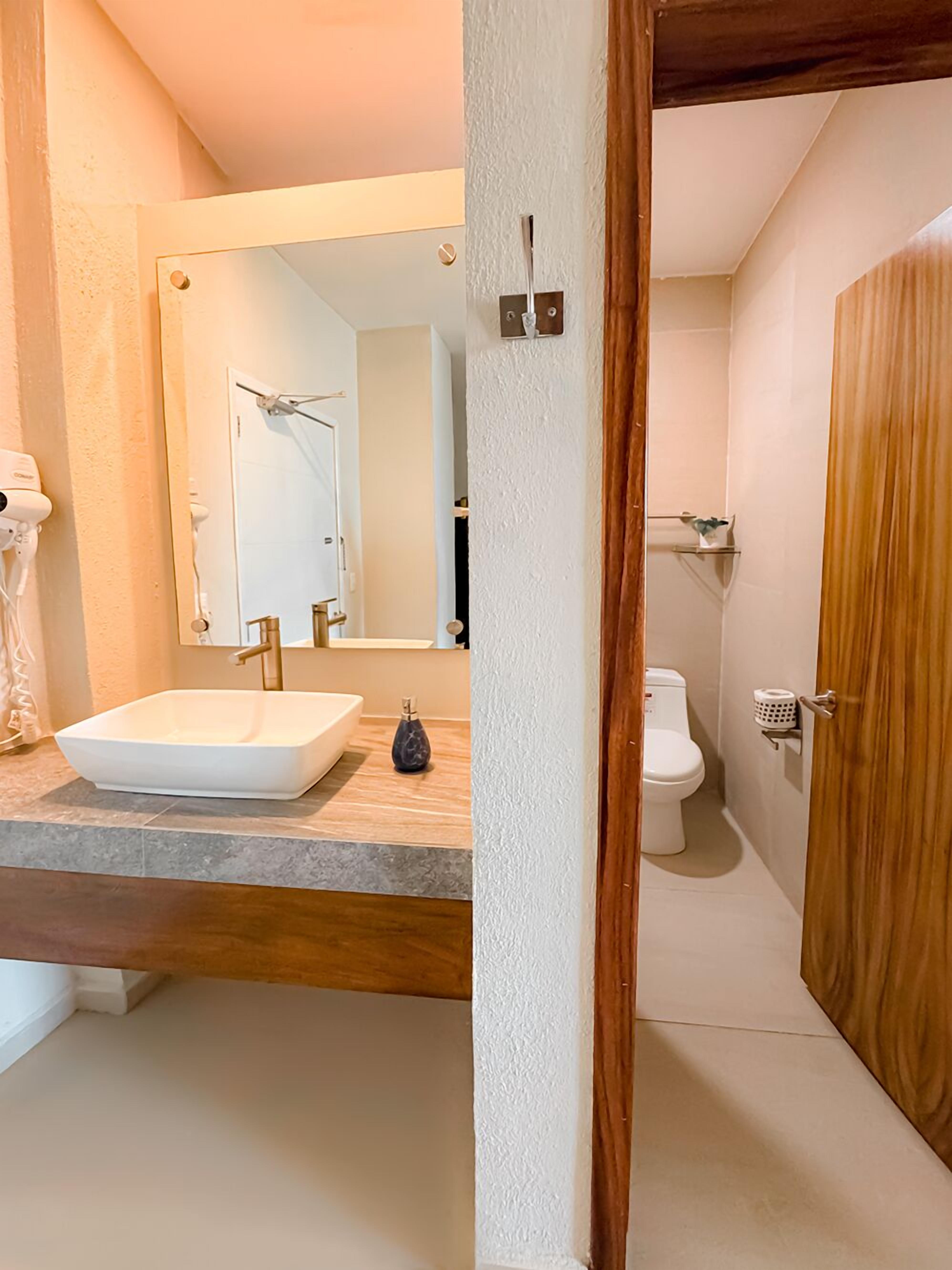 Une salle de bain avec un lavabo blanc, un miroir et une porte en bois.