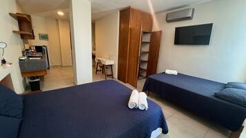 A hotel room with two beds, a desk, a wardrobe, and a TV.