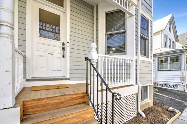 A two-story house with a front porch, wooden steps, and a white door.