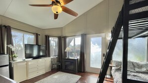 A spacious room with a ceiling fan, a television, a fireplace, and a bed with a ladder. - Silicon Valley Hideaway w/ Private Garden (San Jose)