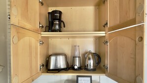 A compact kitchen with wooden cabinets, a coffee maker, a toaster, a blender, a kettle, and a microwave. - Silicon Valley Hideaway w/ Private Garden (San Jose)