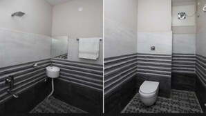 A bathroom with a toilet, sink, and mirror. - Nirmalya plaza (Brahmapur)