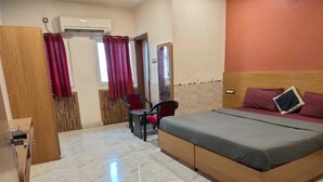 A hotel room with a bed, a desk, and a chair. - Nirmalya plaza (Brahmapur)