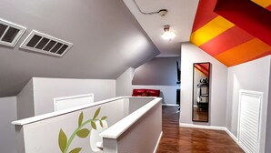 Un intérieur moderne avec un plancher en bois, des murs blancs et un motif décoratif rayé rouge et jaune sur un des murs.