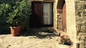 Un bâtiment en pierre avec un toit en tuiles, une porte en bois et une fenêtre avec des volets.