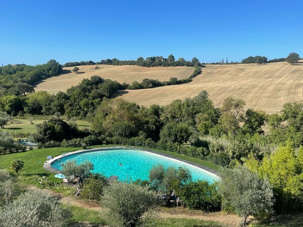 Ein großer, gebogener Pool, umgeben von üppiger Vegetation und Hügeln.