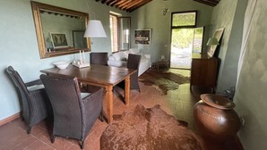 Une pièce rustique avec une table en bois, des chaises en osier, un canapé et un tapis en peau de vache.