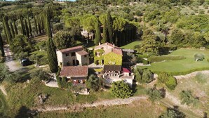 An aerial view of a countryside property with stone buildings, a paved driveway, and surrounding greenery. - Charming Cottage overlooking the pool and the beautiful Tuscan landscape  (Toscana)