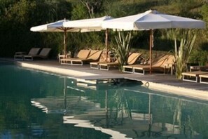 A pool area with lounge chairs and umbrellas.